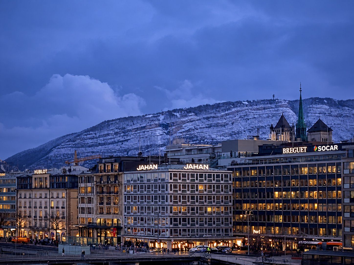 Enseignes lumineuses en toiture sur la rive gauche de Genève au crépuscule, Salève enneigé en arrière-plan