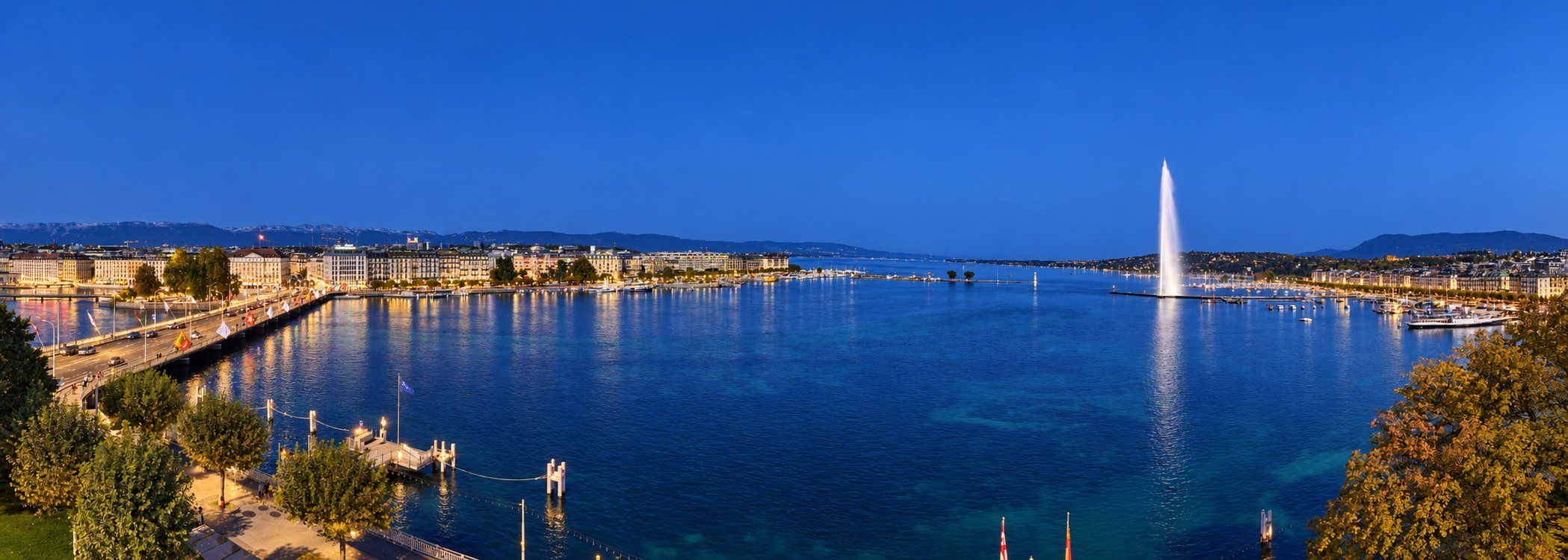 Panorama de la Rade de Genève de nuit avec le Jet d'eau, le pont du Mont-Blanc et les quais illuminés